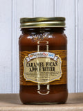 Jar of Caramel Pecan Apple Butter with a gold lid, labeled with product name and description, set against a white wooden