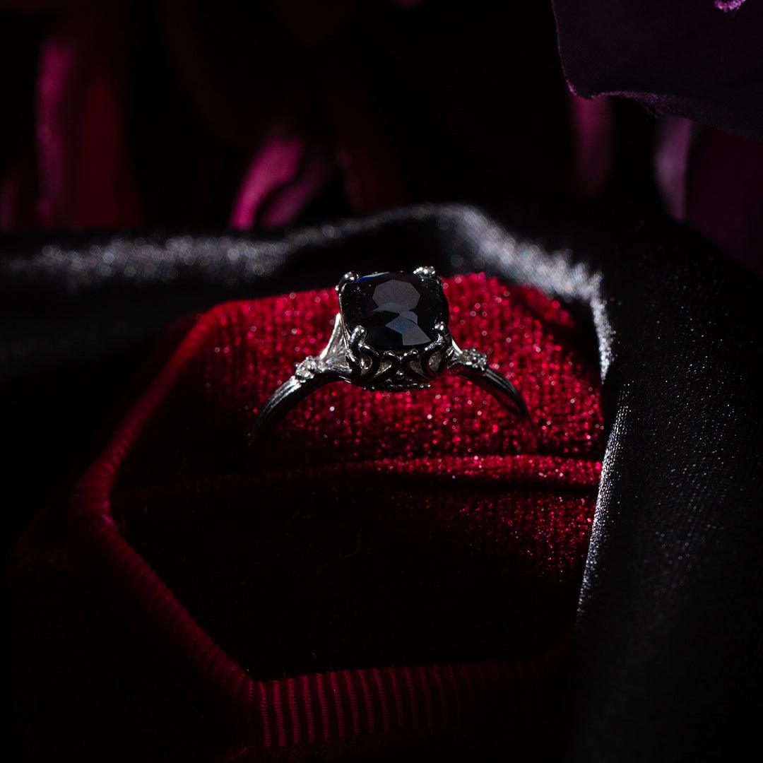 Black Dahlia Satin Collection Jewel Candle with a large black gemstone ring in a red velvet jewelry box.