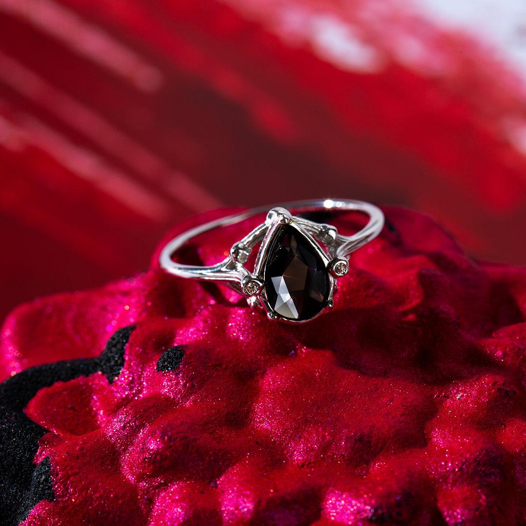 Black Dahlia Satin Collection Jewel Candle ring with a black teardrop gemstone set in silver, resting on a red velvet