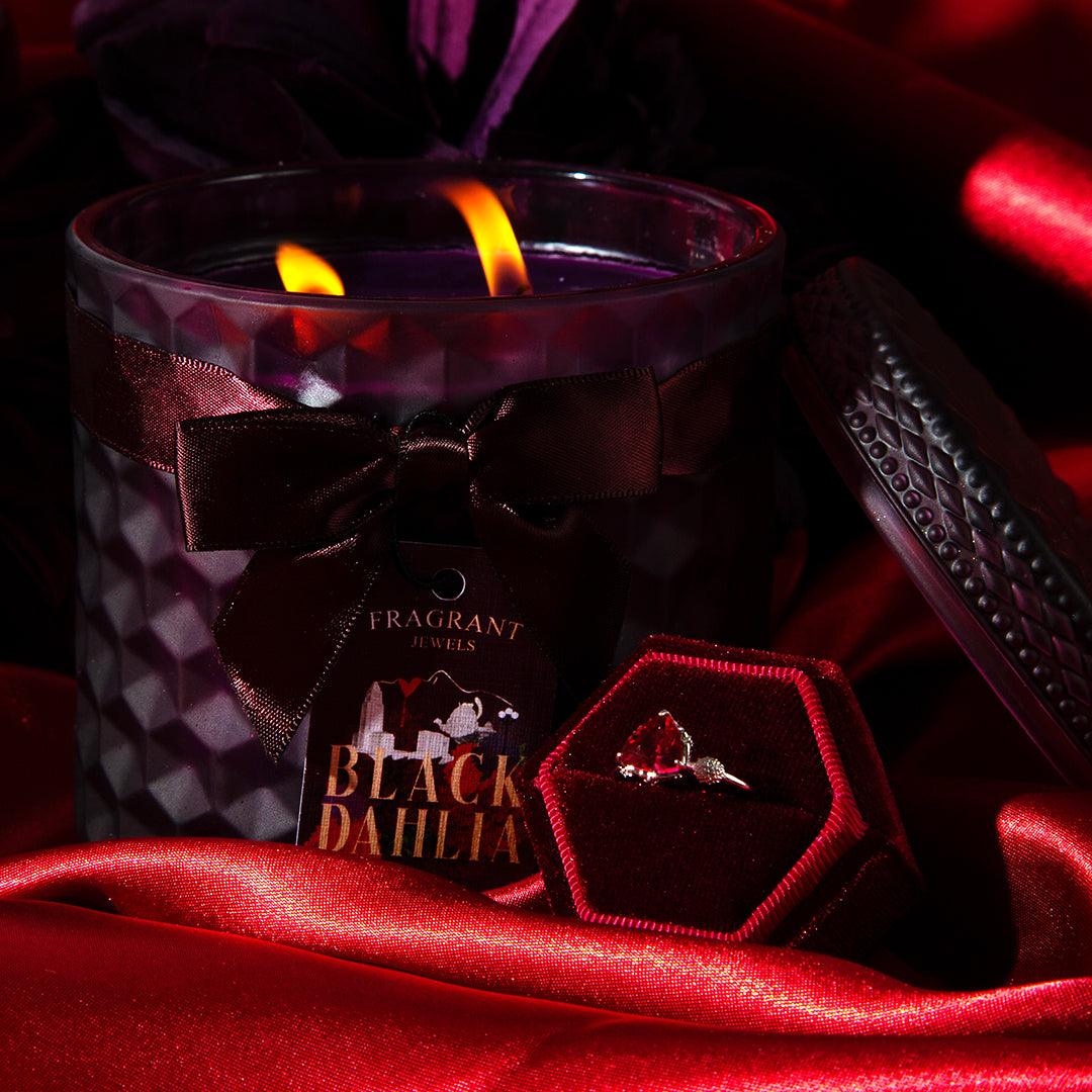 Black Dahlia Satin Collection Jewel Candle with red gemstone ring in velvet box, surrounded by red satin fabric and dark