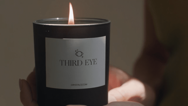 Black Third Eye Candle with a lit flame and minimalist label featuring the brand name.